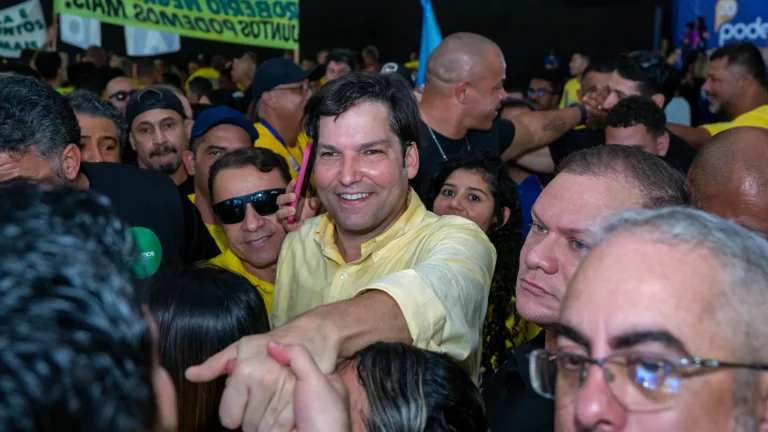 Robério Negreiros sorri e cumprimenta apoiadores em meio a uma multidão vestida de amarelo durante evento do Podemos